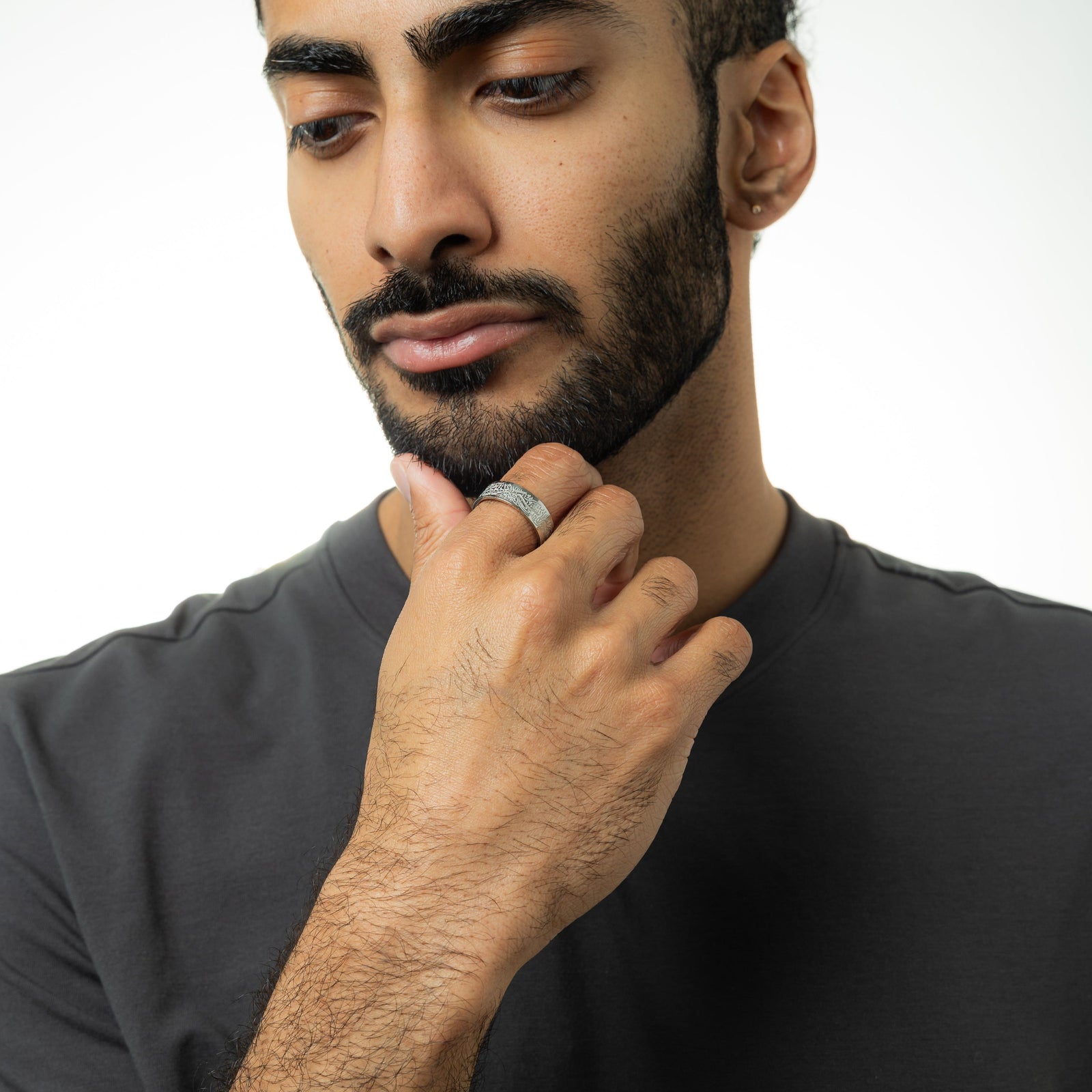 Photo of the model touching their chin with their fingers showing the silver "With Hardship Comes Ease" Ring V2 they are wearing on their right index finger.