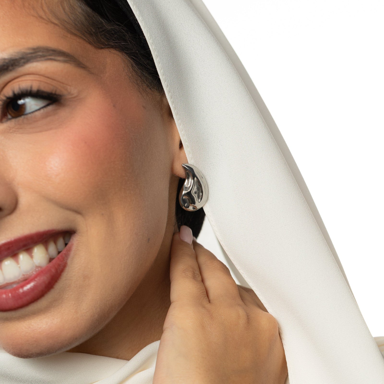 Woman wearing a silver vintage droplet earring and a white headscarf