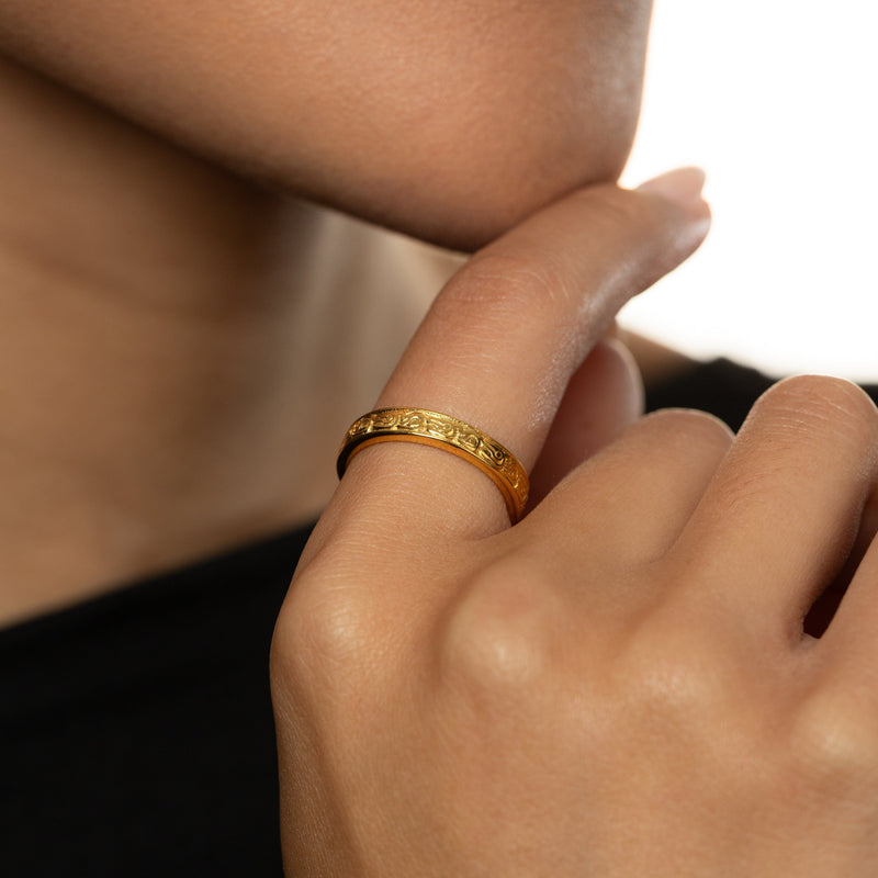 Close-up of a hand wearing a gold vintage heritage ring.