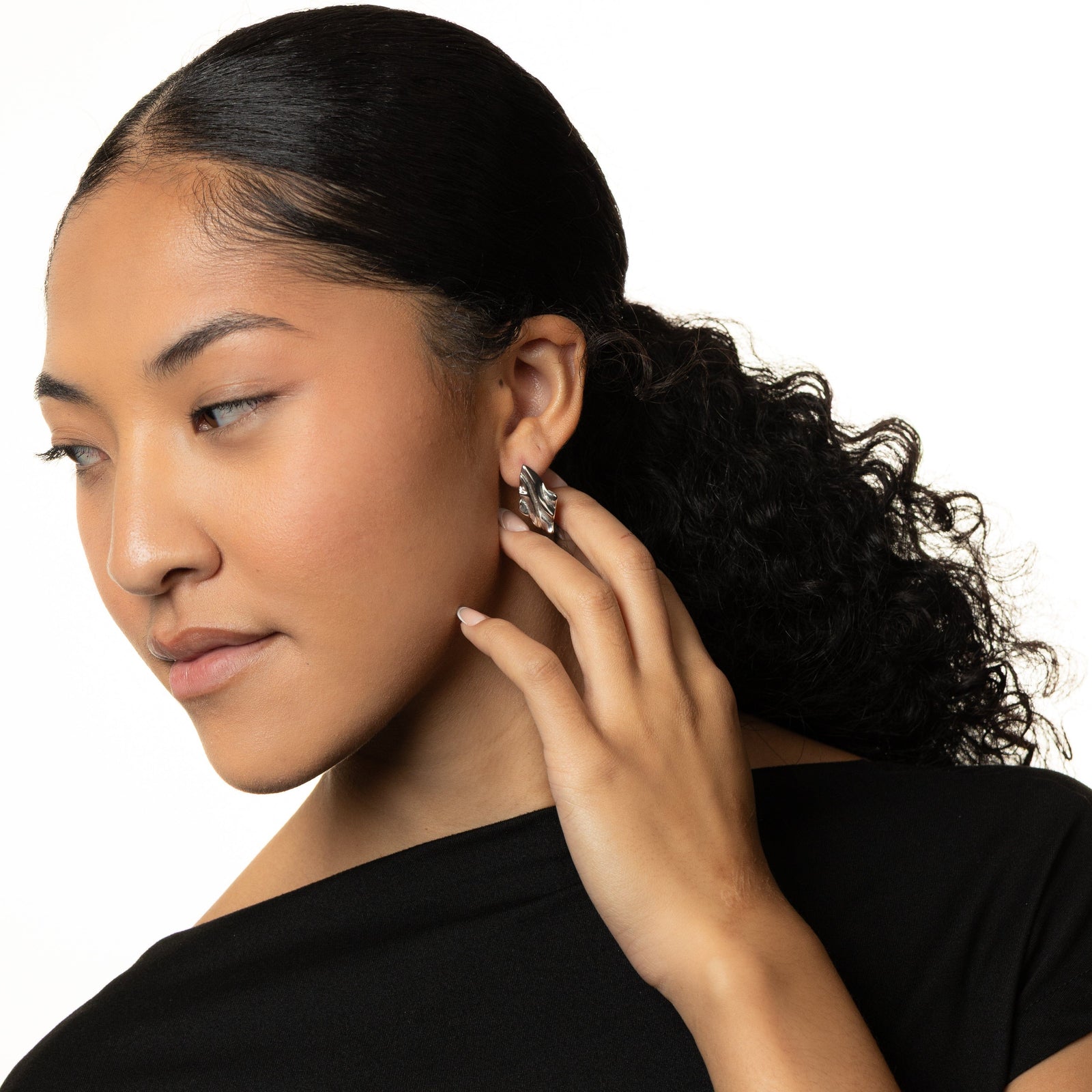 Woman wearing a silver vintage melted earring shot on a white background