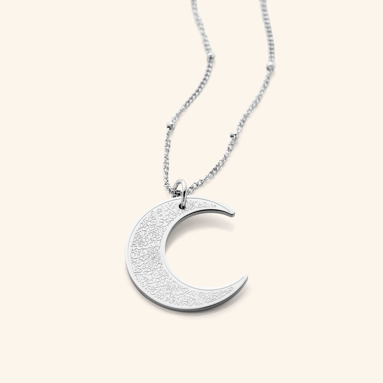 The Ayatul Kursi Crescent Necklace in a polished silver finish, showcasing a crescent pendant adorned with detailed Arabic inscriptions, hanging from a fine silver chain.