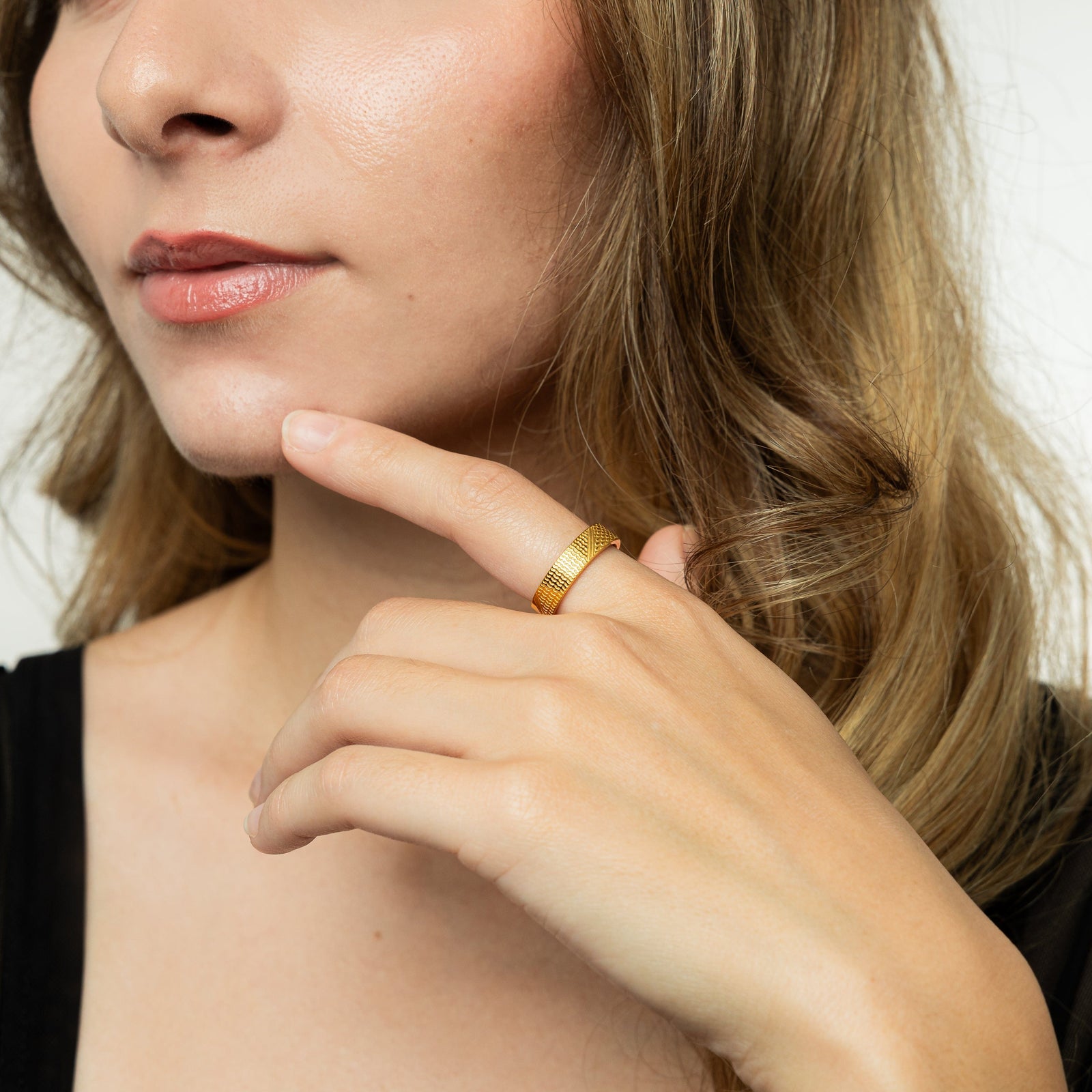 A female model wearing the 18K gold plated Keffiyeh Ring on her index finger. 
