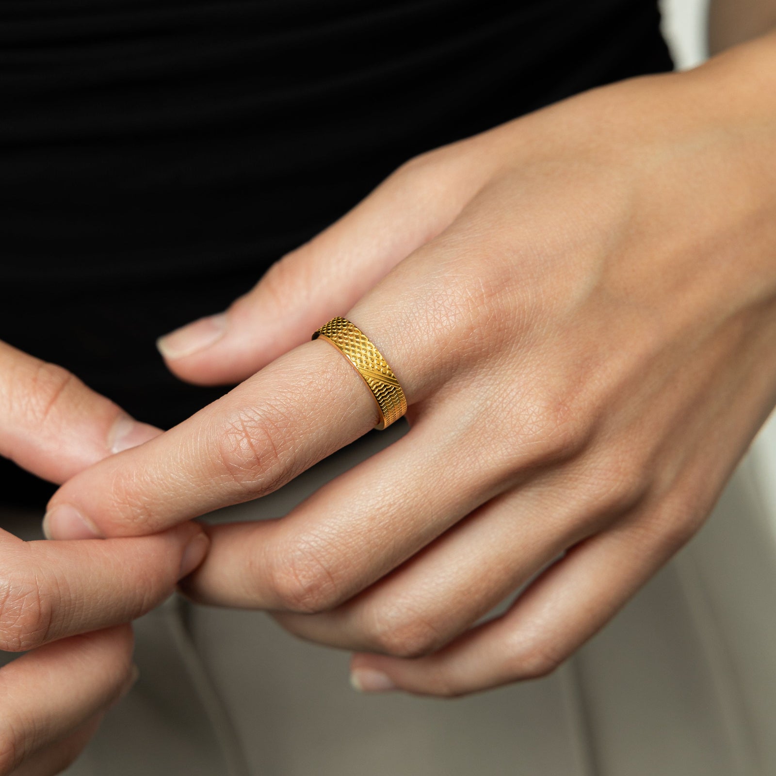A female model wearing the 18K gold plated Keffiyeh Ring on her index finger. 