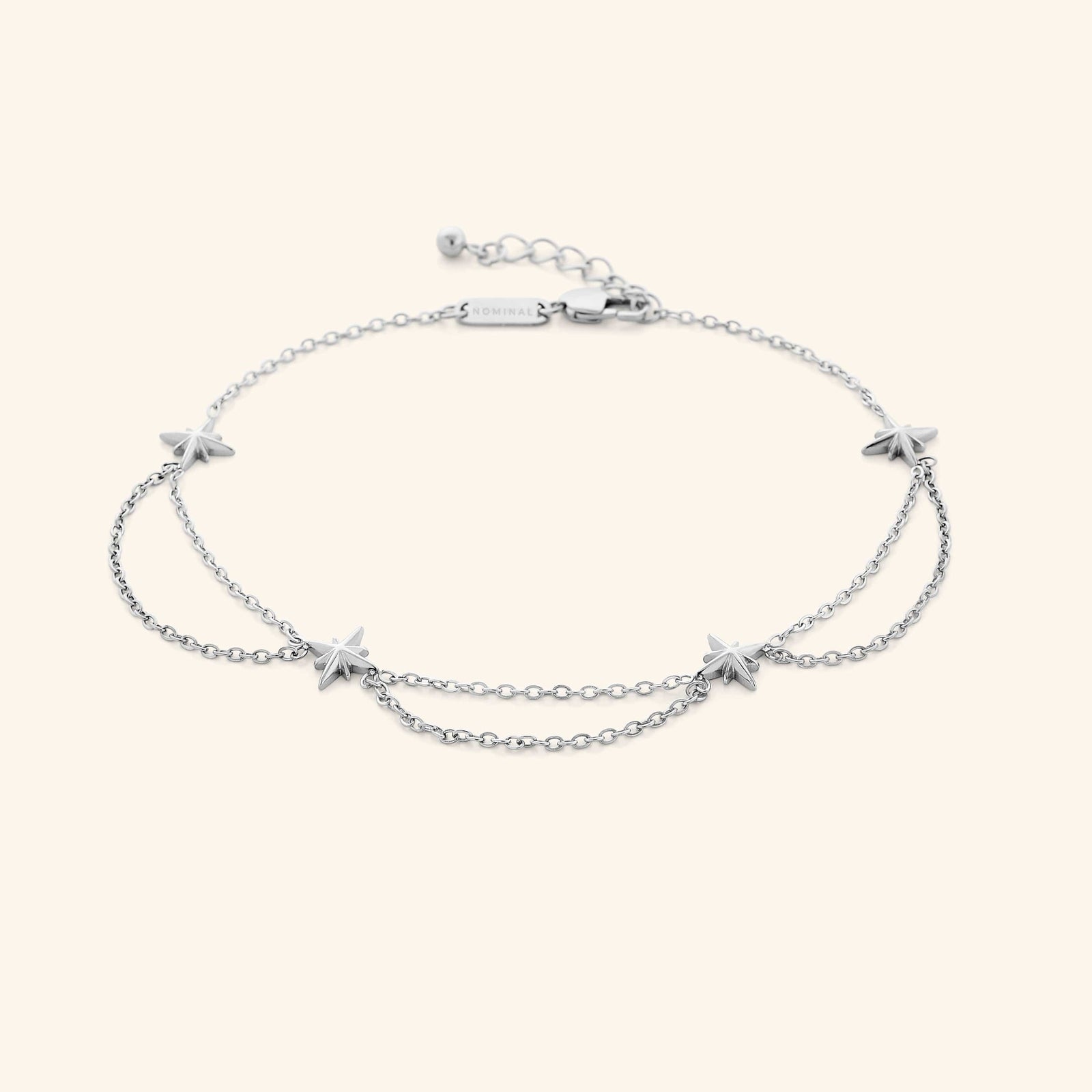 A silver anklet that features north stars all along the chain, drooping chains connecting each one design.
