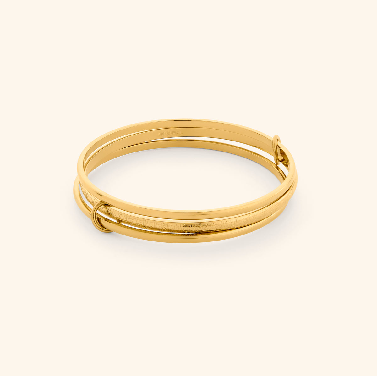 The Ayatul Kursi Bangle Stack by Nominal, featuring interlocking 18k gold-plated bands engraved with Arabic calligraphy, displayed on an off-white background.