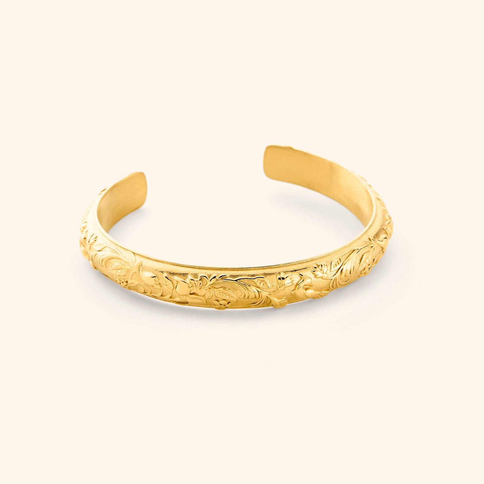 An 18K gold plated cuff etched with jasmine, marigolds, and water lilies art.