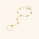The Bezel Bloom Hand Chain by Nominal, crafted with an 18k gold-plated finish featuring delicate floral bloom charms centered with sparkling bezel-set crystals along the wrist and finger loops, displayed on an off-white background.