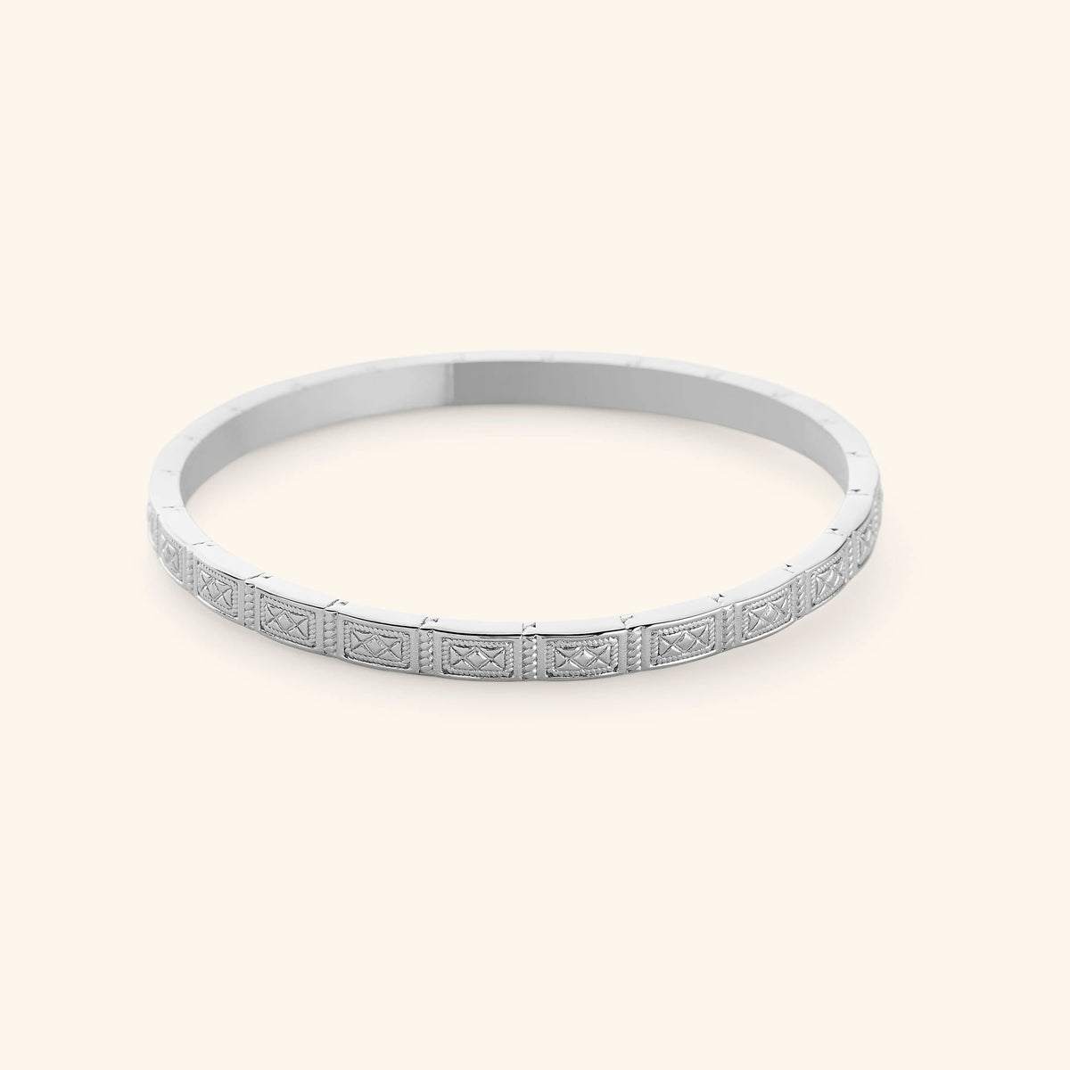 A slim silver bangle etched with geometric patterns pulled from Damascus tilework.