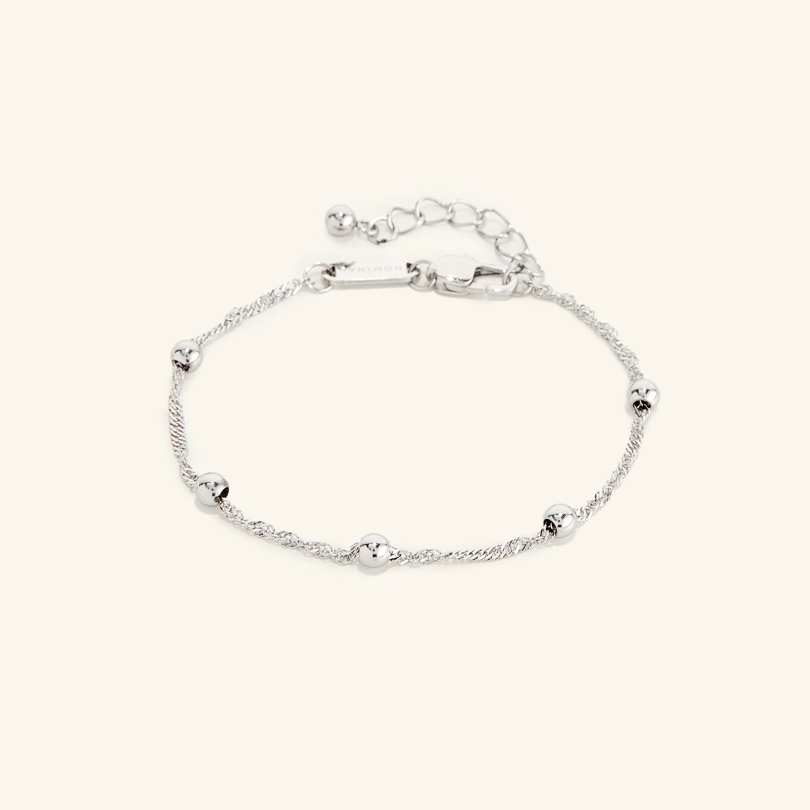Flat lay of a silver bracelet. The Dotted Twisted Bracelet features a spiraling chain that brings gorgeous dotted beads together for the perfect touch.