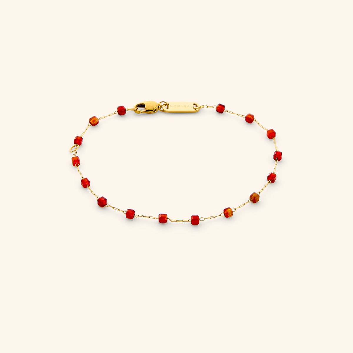The Essential Red Agate Micro Bracelet by Nominal, featuring a delicate 18k gold-plated chain accented with faceted rich red agate beads and secured with a lobster clasp on an off-white background.