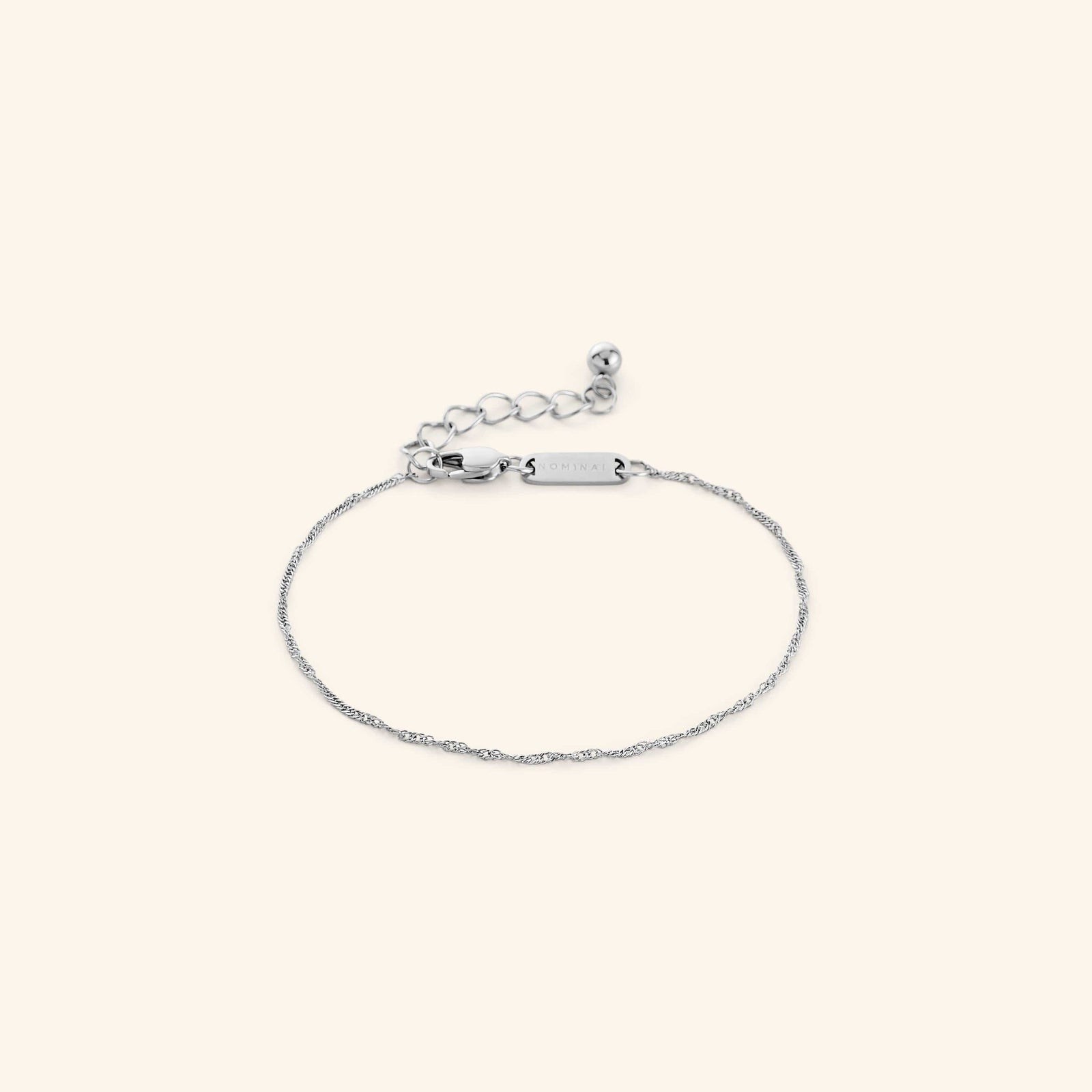 Flat lay of a silver Micro Twisted Bracelet. The Invisible Twisted Bracelet features a 1MM twirling chain pattern.