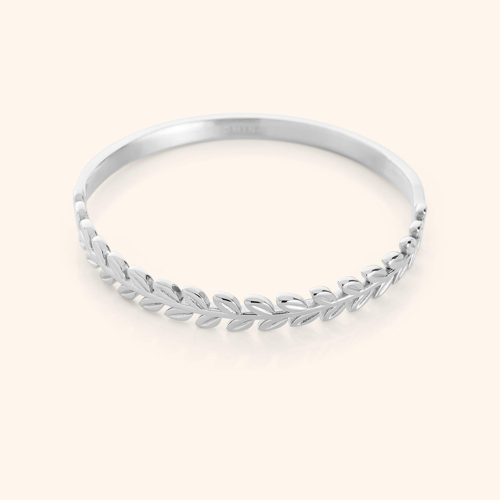 The Palestine Olive Layering Bangle in a polished silver finish, showcasing a twisted olive branch motif on one half and a smooth, minimalist band on the other, combining traditional symbolism with contemporary design.