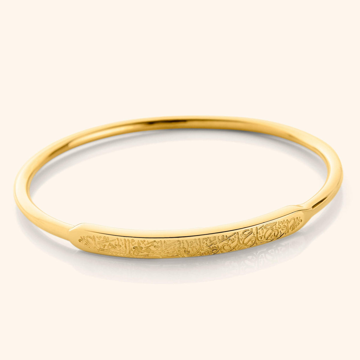 Close-up of the Rumi Bangle in 18K gold plating, featuring the engraved quote “These pains you feel are messengers. Listen to them” on the outer surface