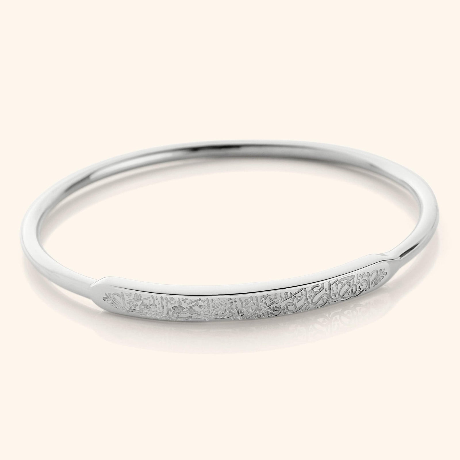 The bangle displayed in polished silver, highlighting the same engraved Rumi quote on its exterior.