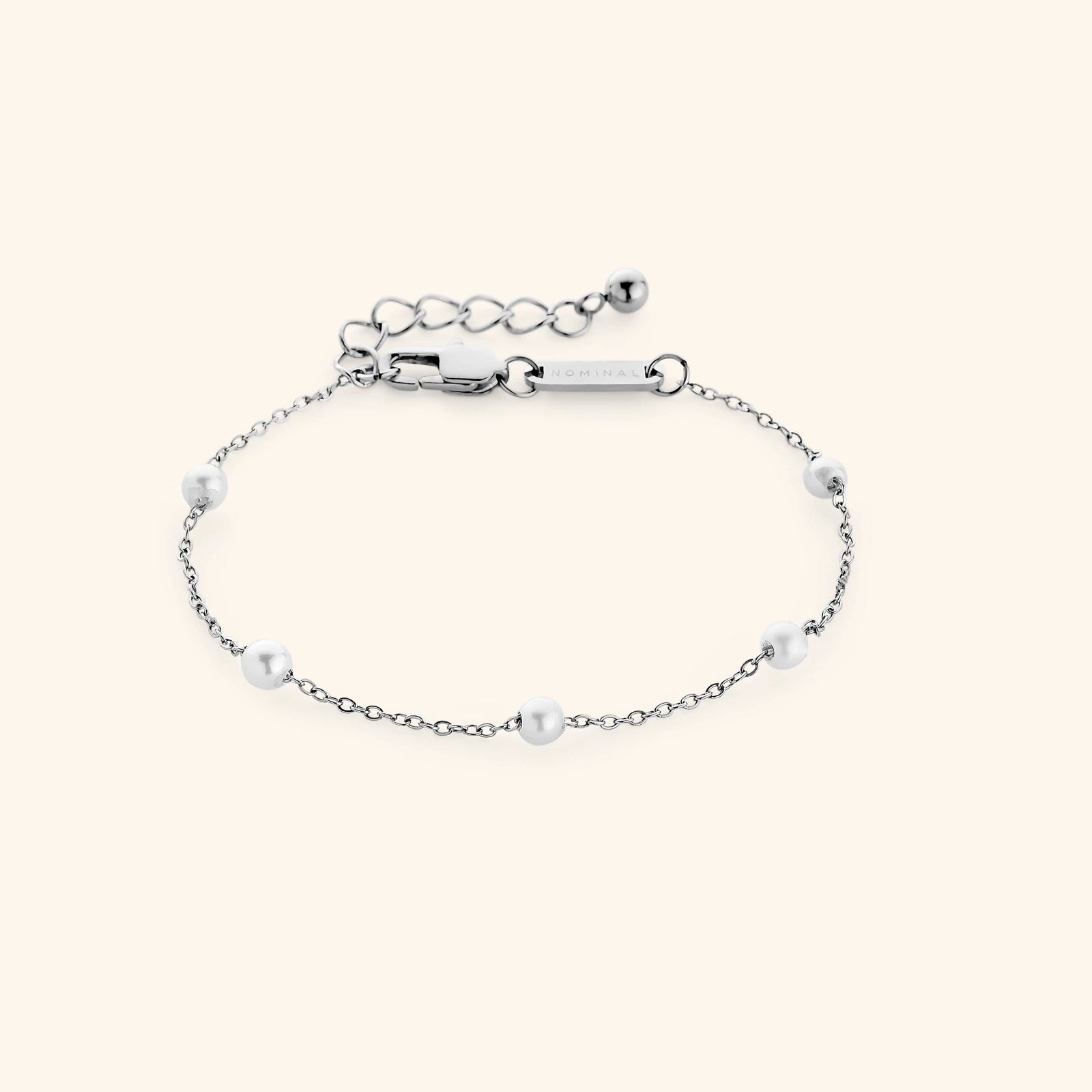 Flat lay of a silver bracelet. The Pearl Strand Bracelet features an array of pearls along a cable chain.
