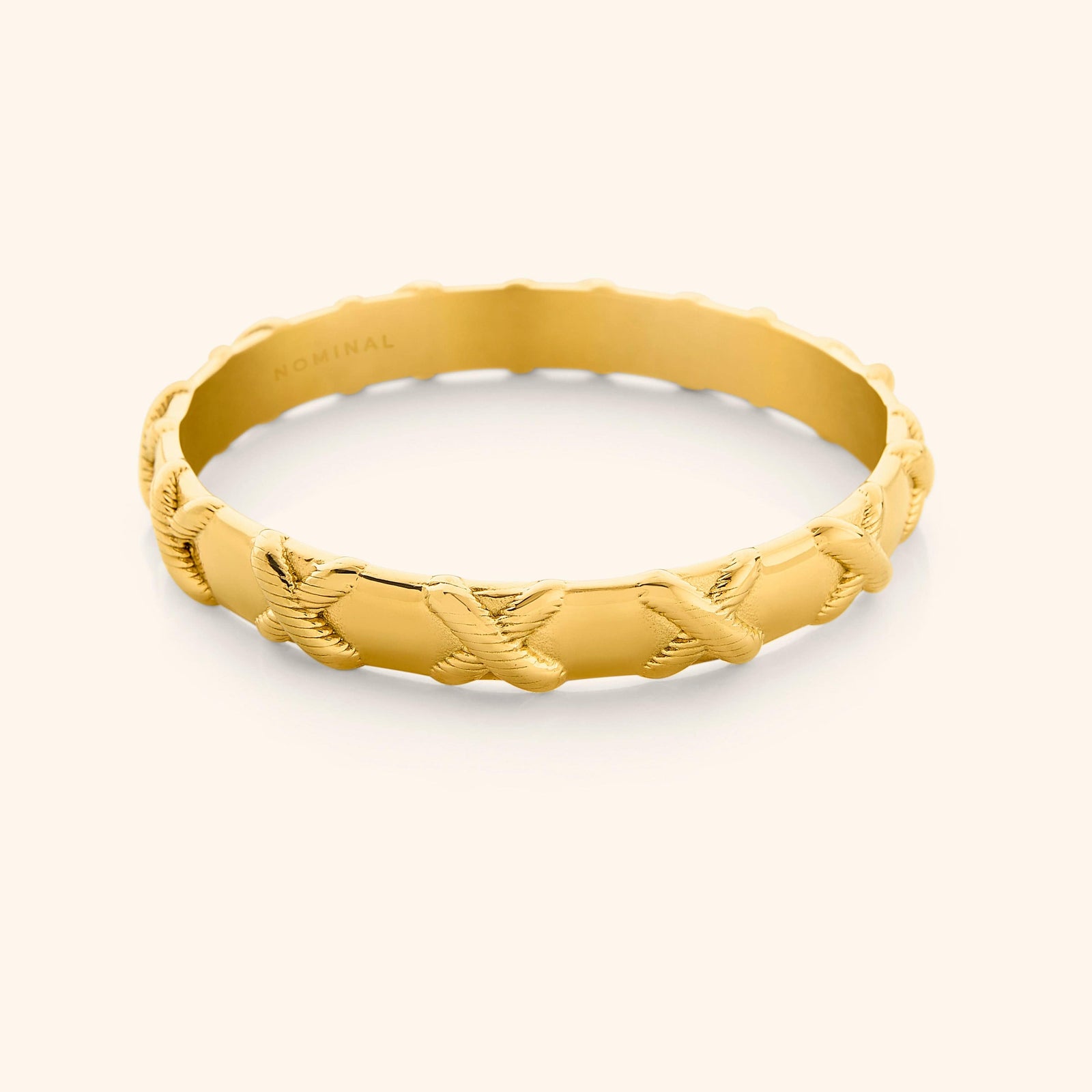 Photo of an 18k gold plated bangle that is designed with embossed X around the bangle.