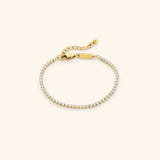 18k gold-plated Tennis Bracelet featuring a continuous strand of round clear crystals with an adjustable extension chain.