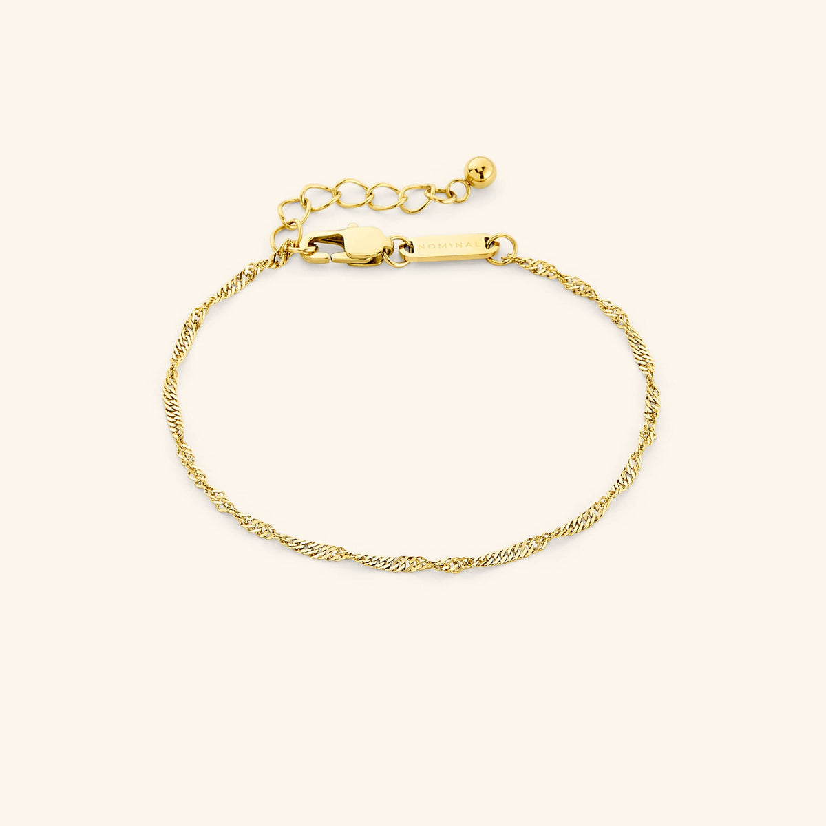 Close-up of the thinnest gold twisted chain bracelet laid flat on a cream background, featuring a lobster clasp and extender chain. Visible text “NOMINAL” engraved on the gold tag.
