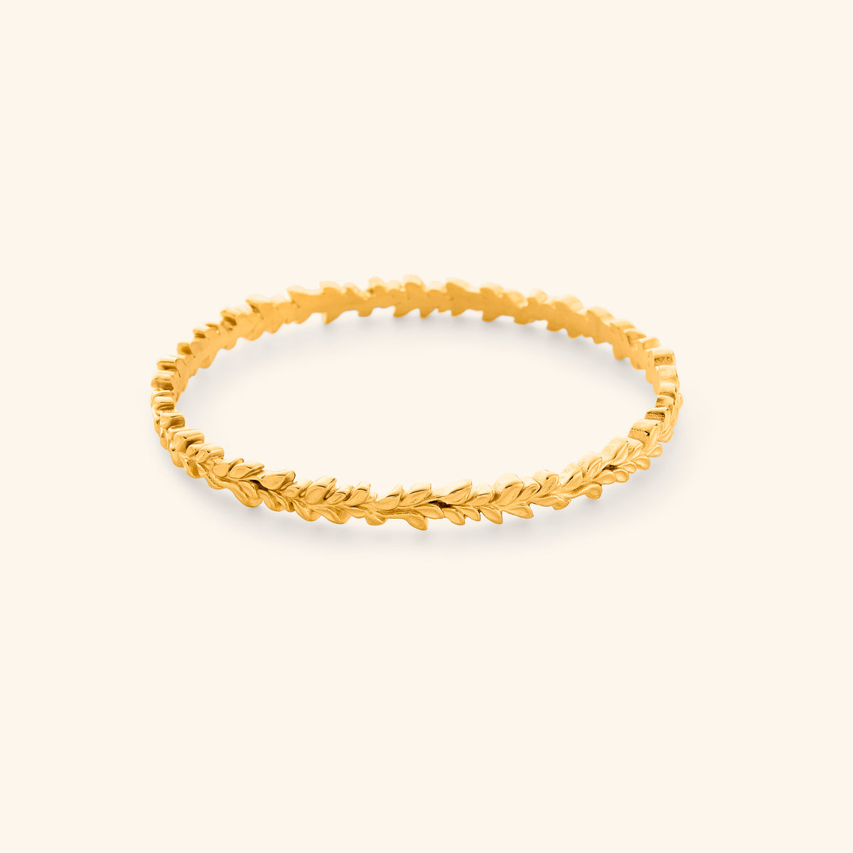 The Weaving Olive Branch Bangle by Nominal, crafted with an 18k gold-plated finish featuring an intricate, continuous sculpted olive leaf design, displayed on an off-white background.