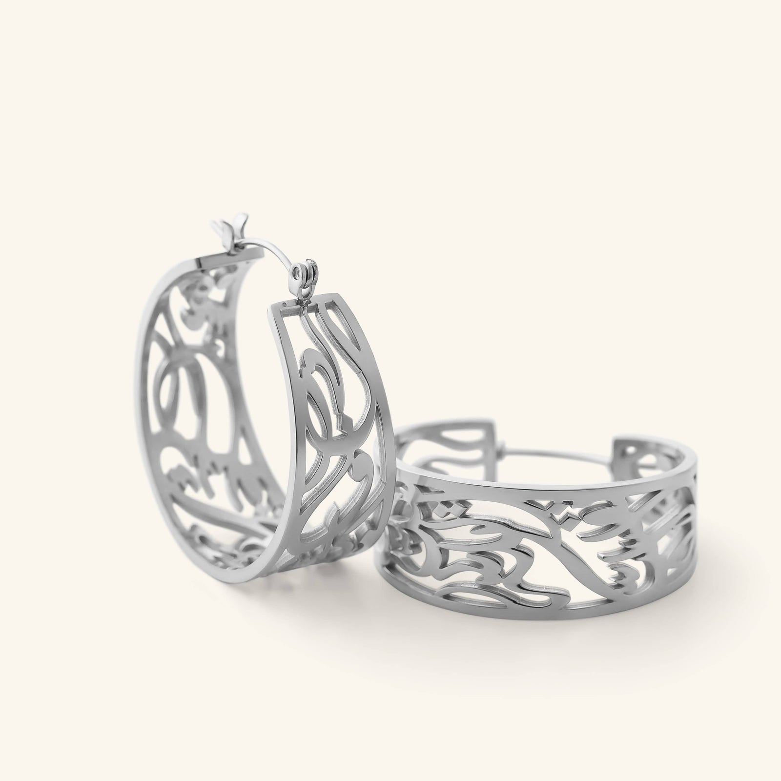 Close-up of the silver “Allah does not burden a soul beyond what it can bear” Earrings, showing the open-cut Arabic calligraphy hoop design.