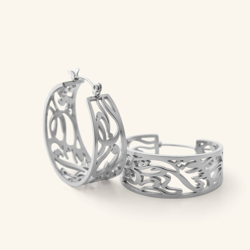 Close-up of the silver “Allah does not burden a soul beyond what it can bear” Earrings pimage_ showing the open-cut Arabic calligraphy hoop design.