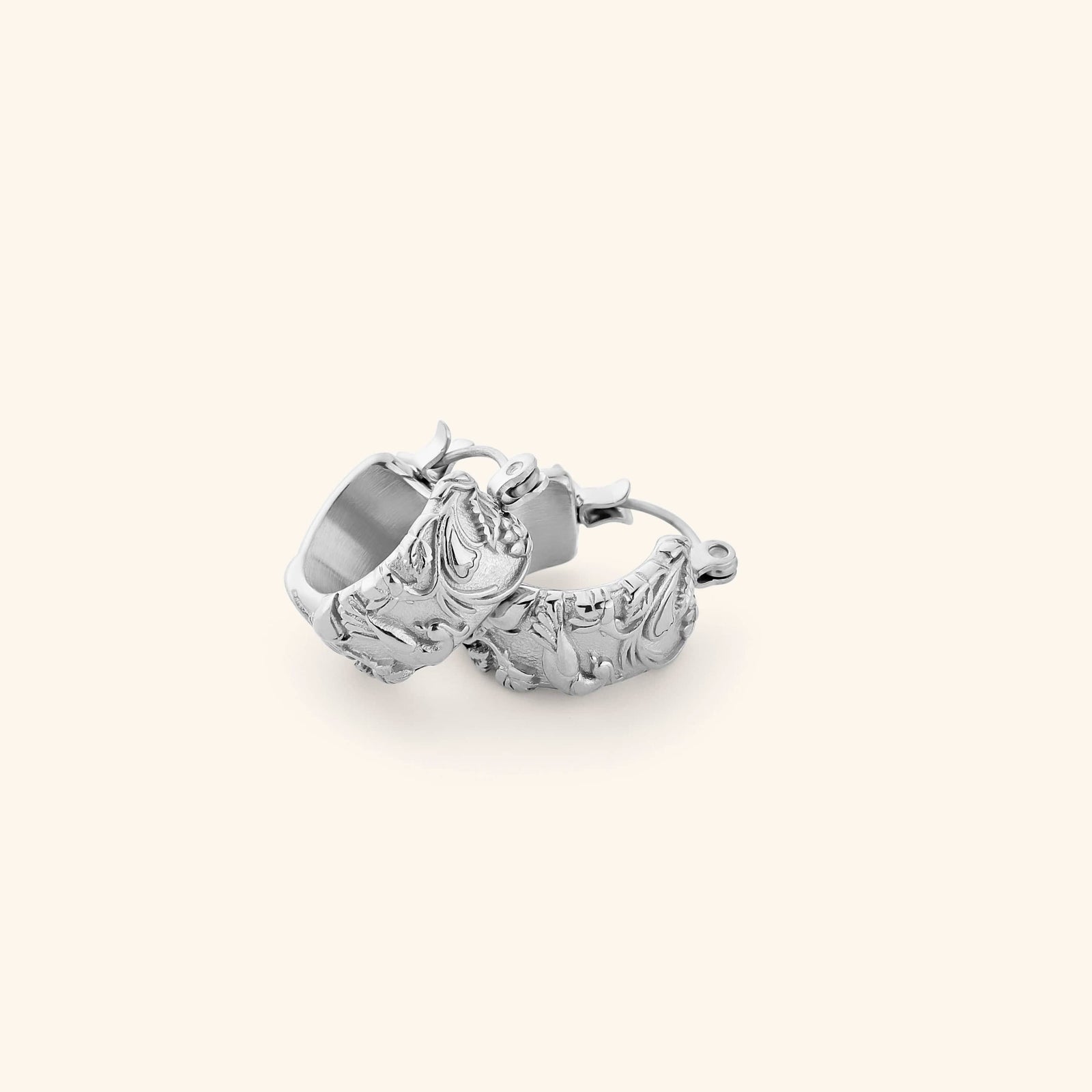 A pair of silver thick hoop earrings wrapped in jasmine, marigolds, and water lilies across the entire surface