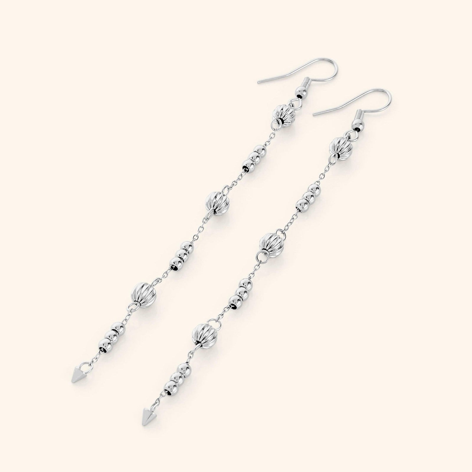 Flat lay of the silver earrings. Comet Earrings drop 3.5 inches with delicate, evenly spaced orbs.