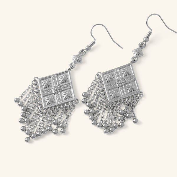 Silver Dancing Kite Earrings featuring square engraved motifs with dangling chains, shown against a neutral background.