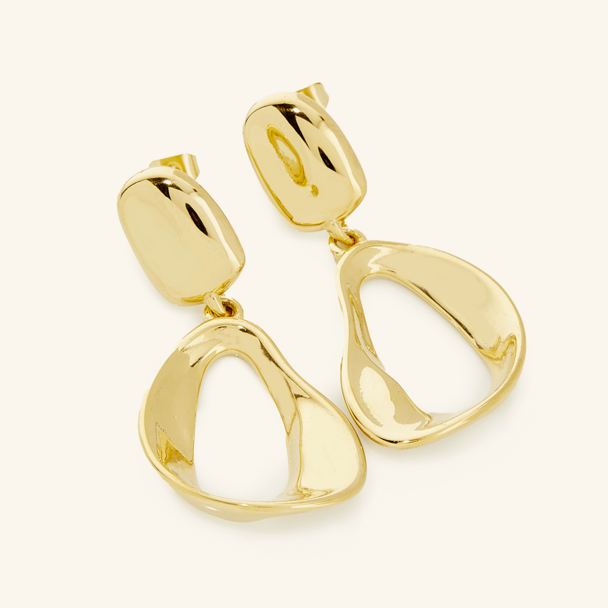 A pair of 18k gold plated earrings. The Droop Earrings features a design that is held by a melted stud and then dropping into statement-like melting oval hoops 