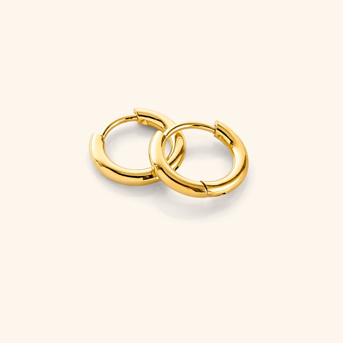Flat lay of the 18k gold plated Huggie Essential Hoops | 8mm against a white background.