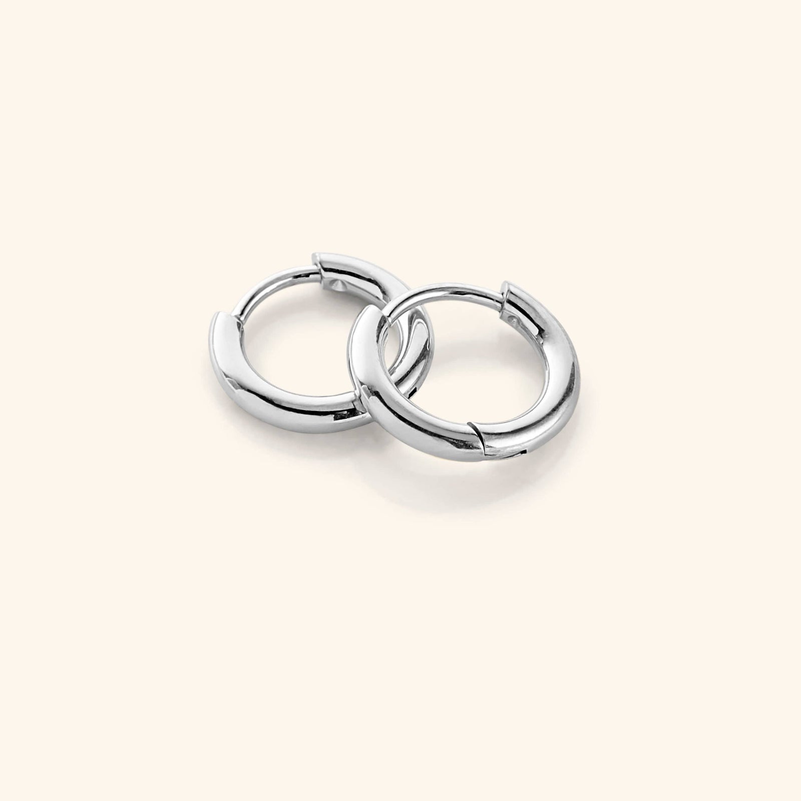 Flat lay of the silver Huggie Essential Hoops | 8mm against a white background.