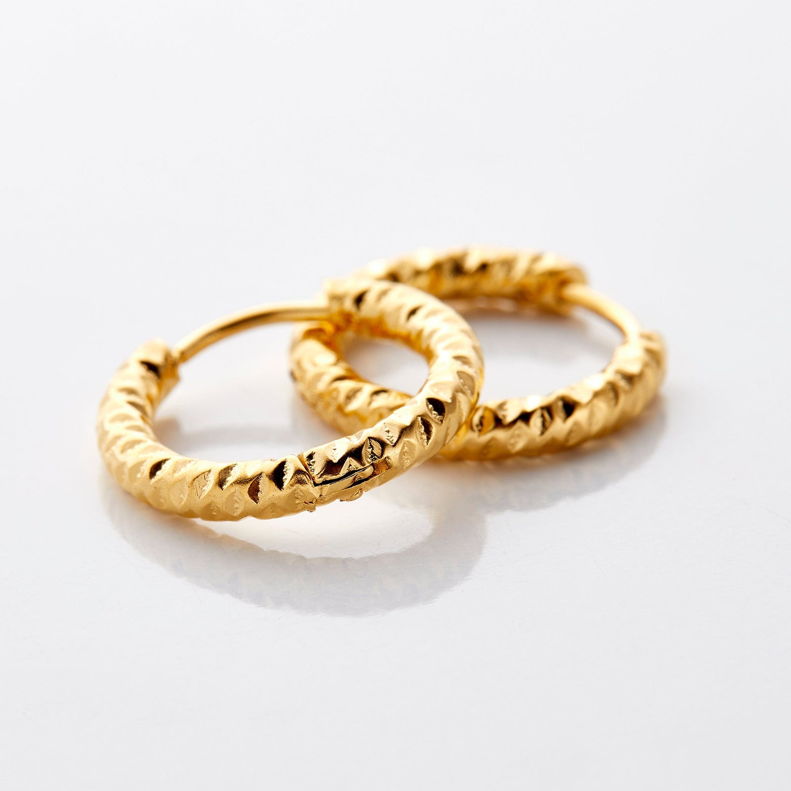 Close up of the gold Flake Hoops on a white background.