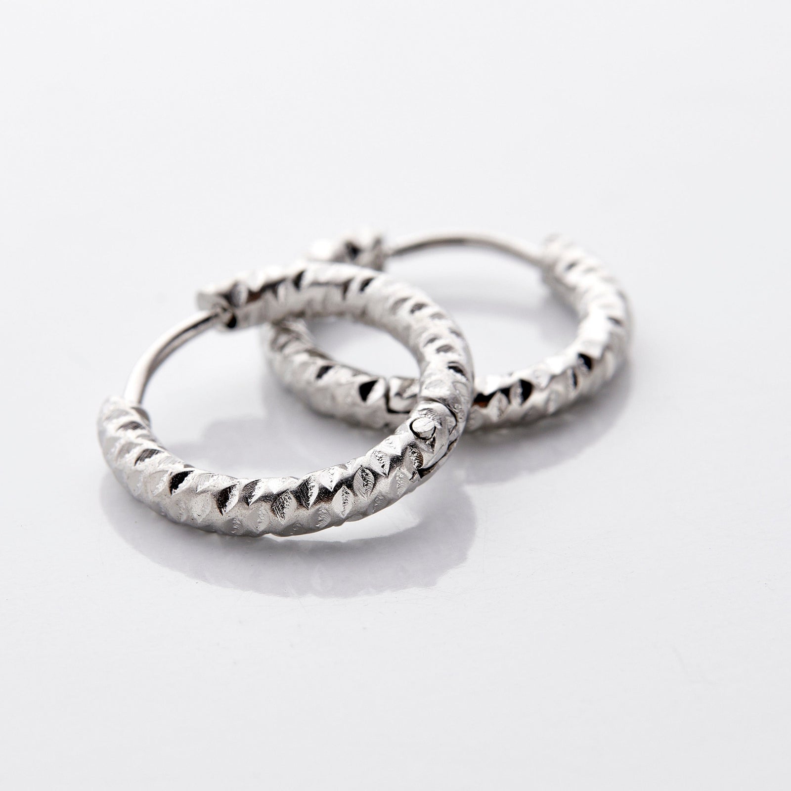 Close up of the silver Flake Hoops on a white background.