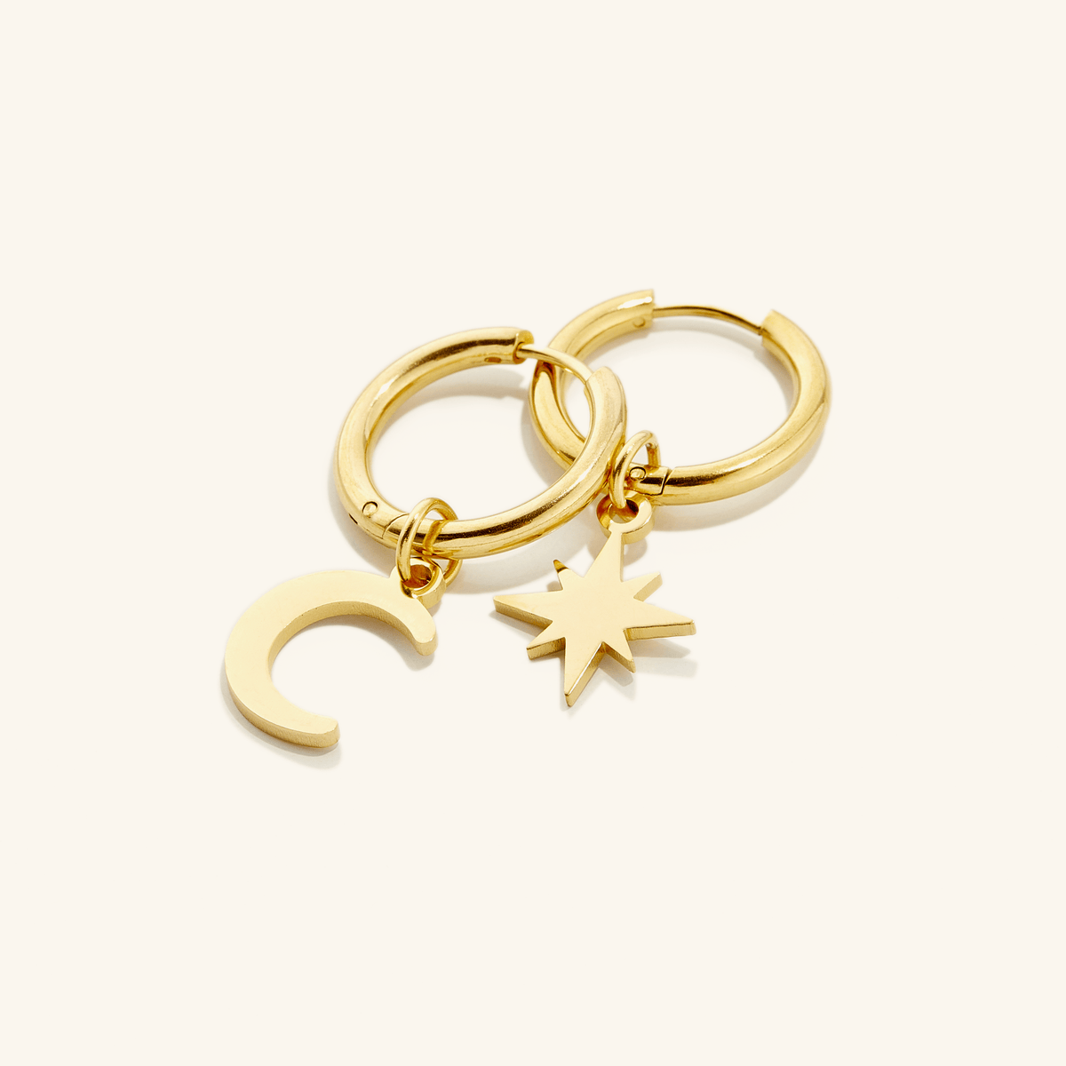 A pair of 18k gold plated hoop earring, one piece features a star charm and the other, a crescent moon charm.