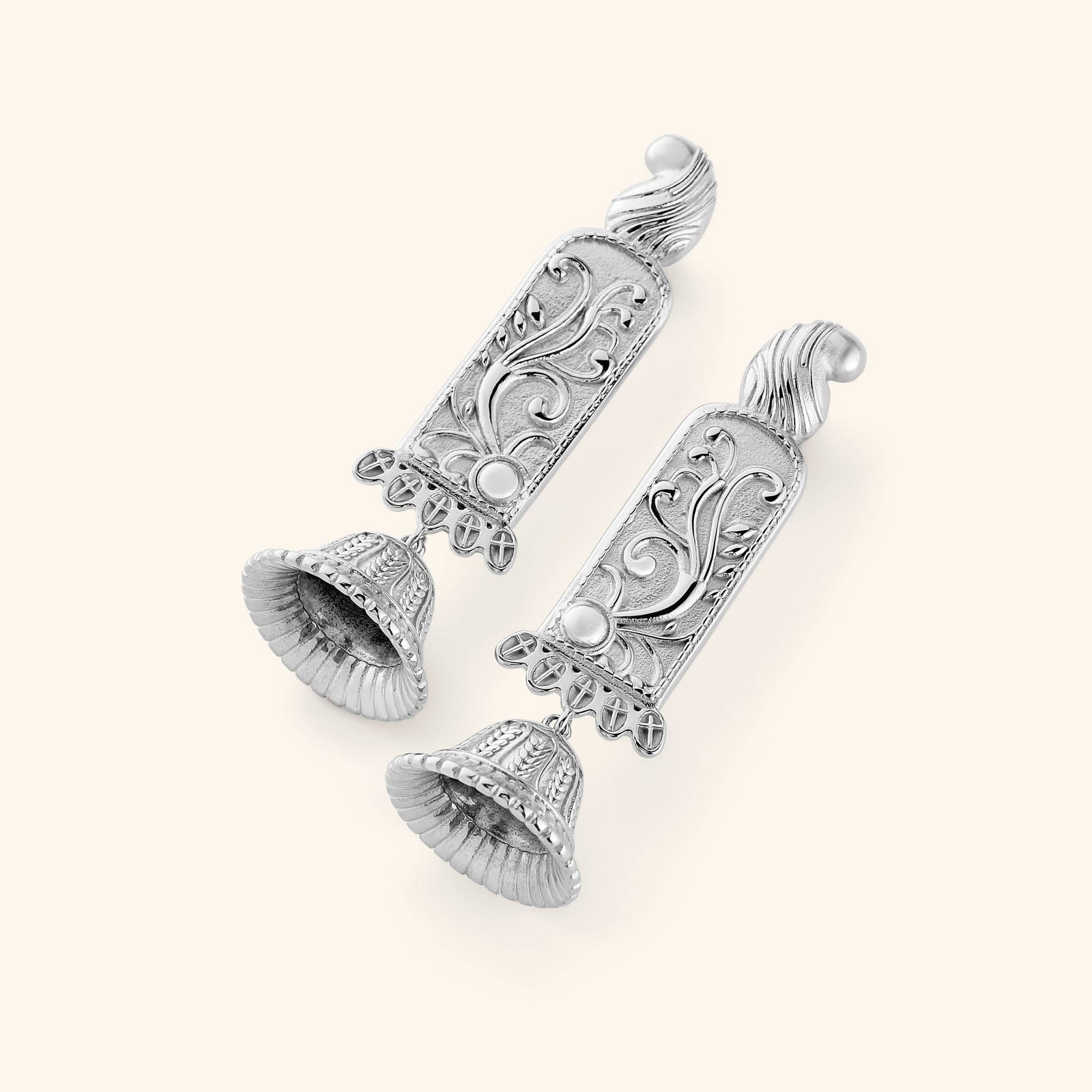 A pair of silver statement jhumkas with paisley-adorned bodies carved in floral detail, each one finished with a ridged dome beneath. 