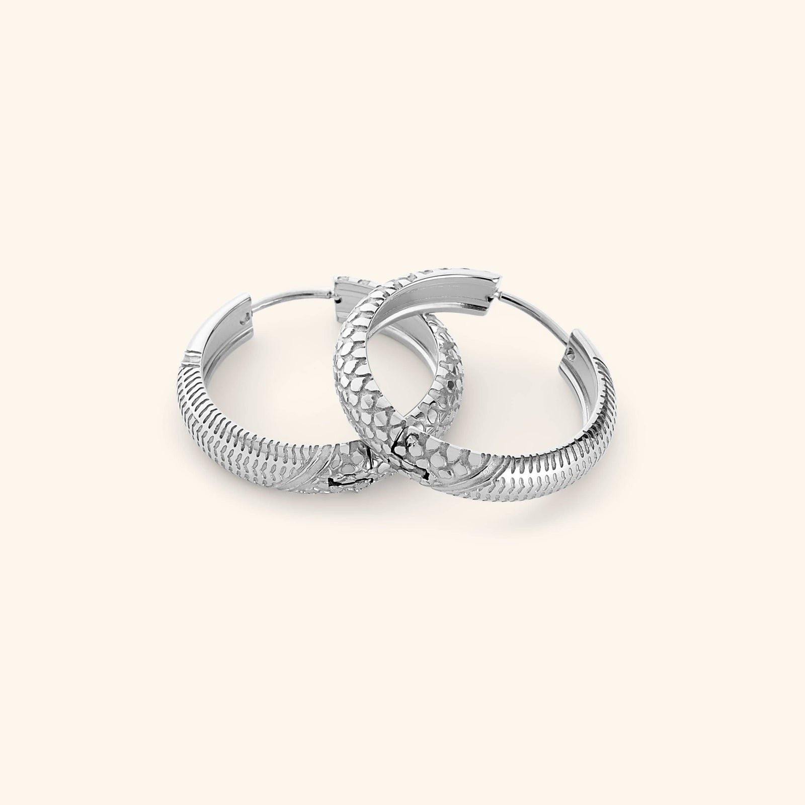 A pair of silver  hoop earrings etched with the Palestinian keffiyeh’s timeless pattern