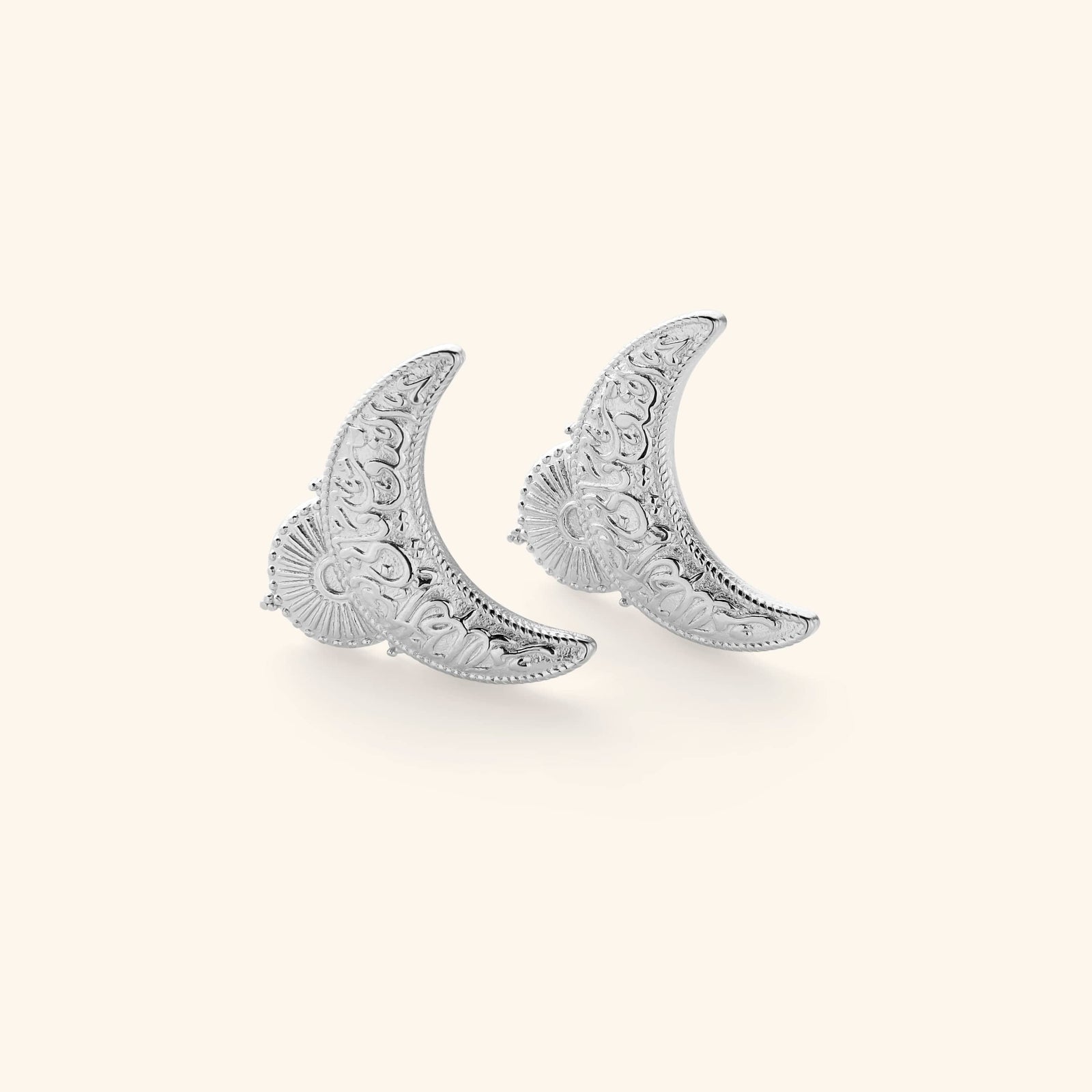 Silver earrings shaped in an upside down crescent featuring an Arabic quote inscribed on each saying "light comes after darkness."