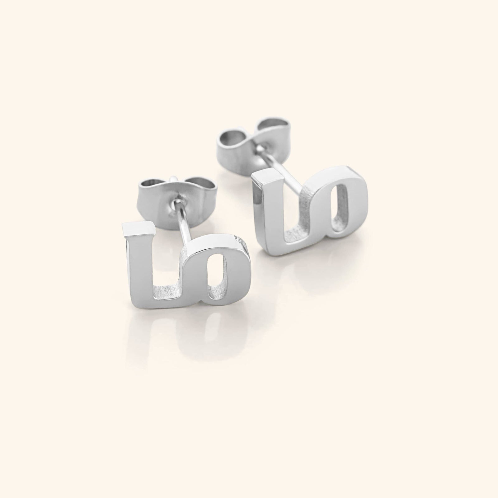 The "Mama" stud earrings in a polished silver finish, showcasing the Arabic letter "م" ("Meem") on each earring. When paired, they complete the word "ماما" ("Mama"), offering a sleek and timeless tribute to motherhood.