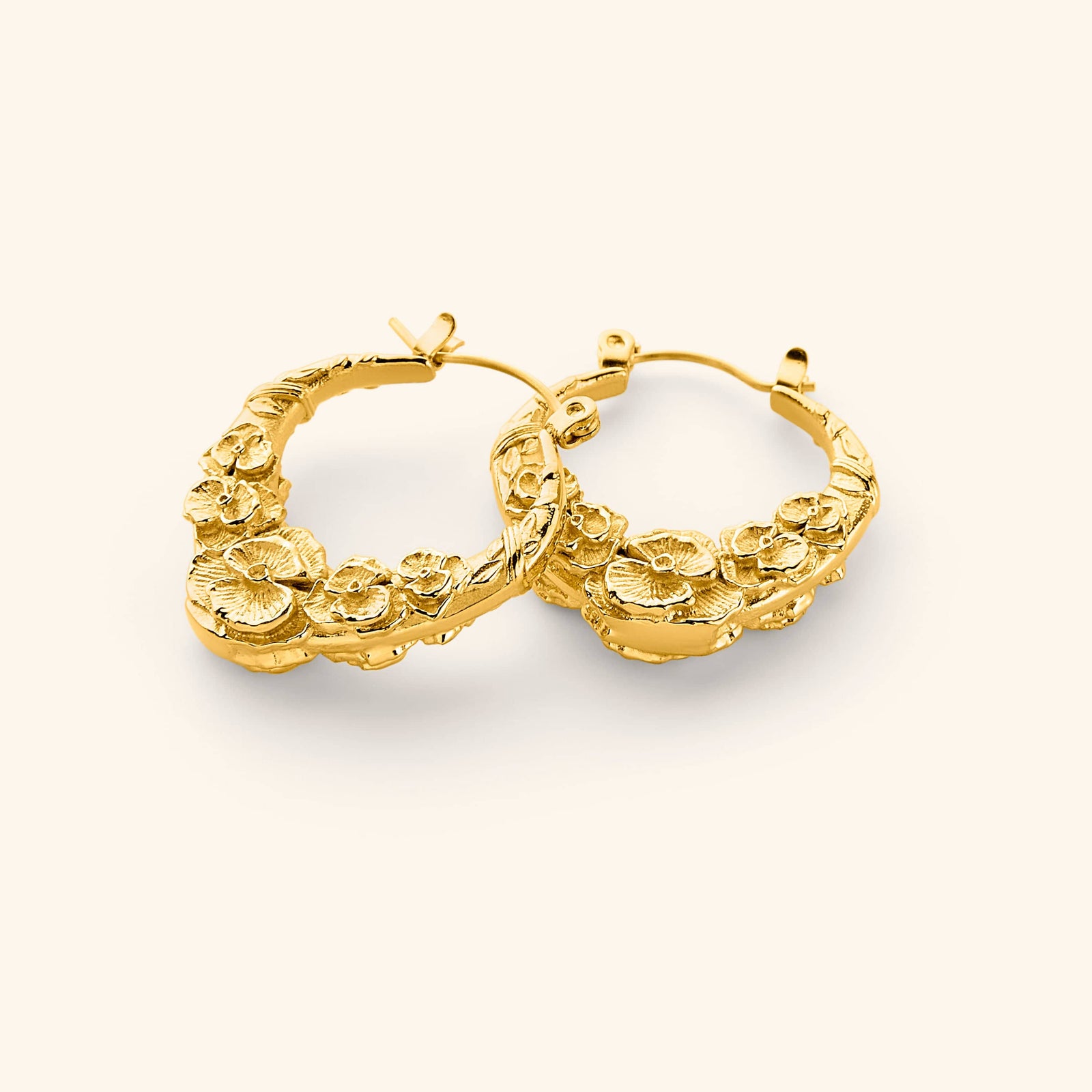 A pair of 18k gold plated hoop earrings that features sculpted poppy flower design.