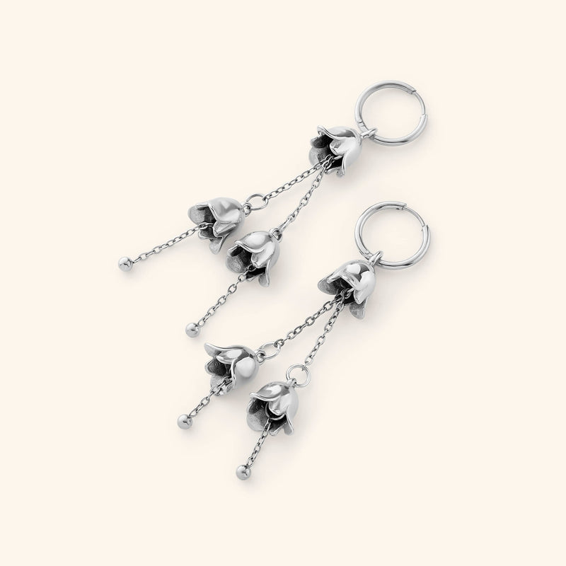 A pair of Roaming Earrings in silver pimage_ showcasing the same floral-inspired dangling design on fine chains attached to hoops.