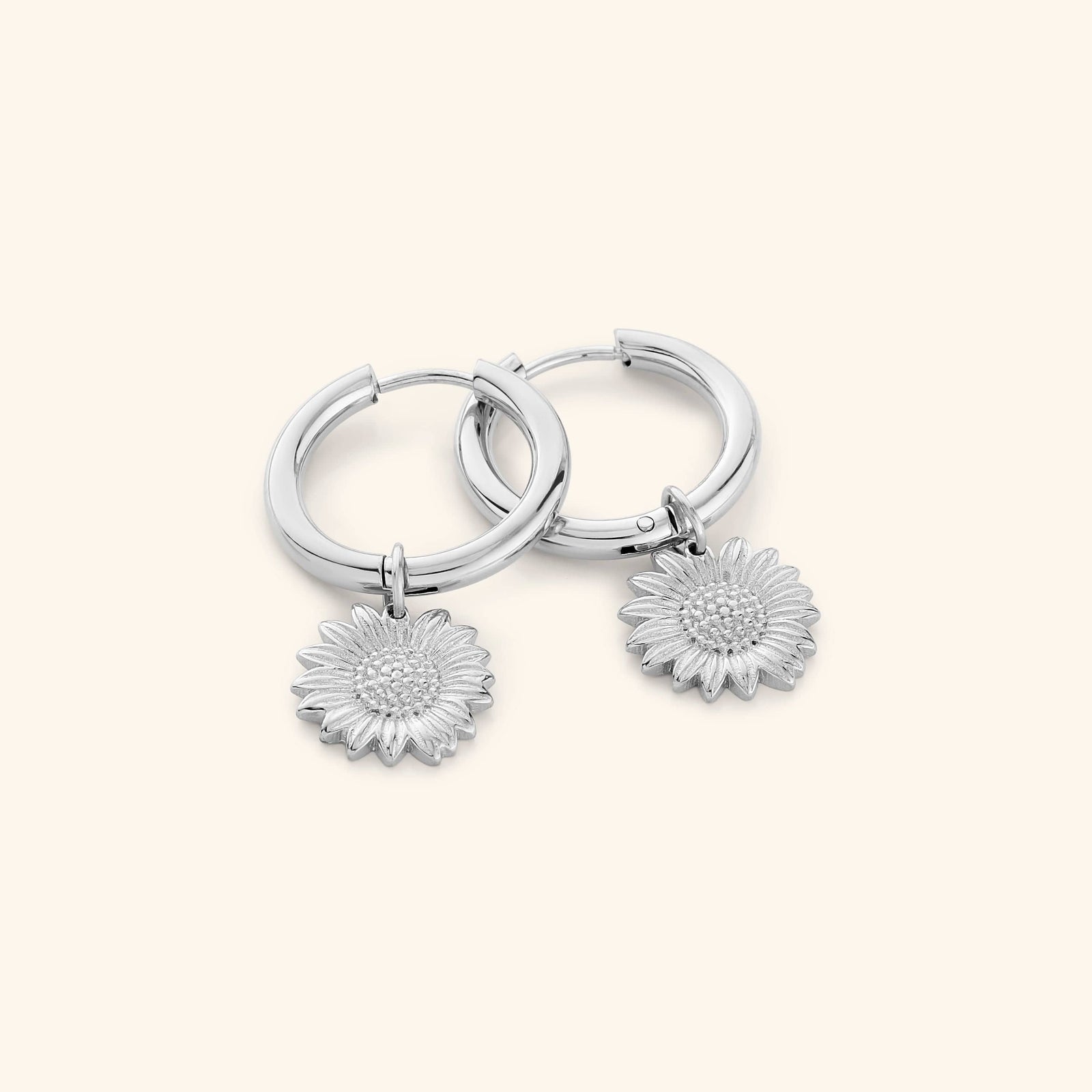 A pair of silver hoop earrings that features sunflower shaped charm.