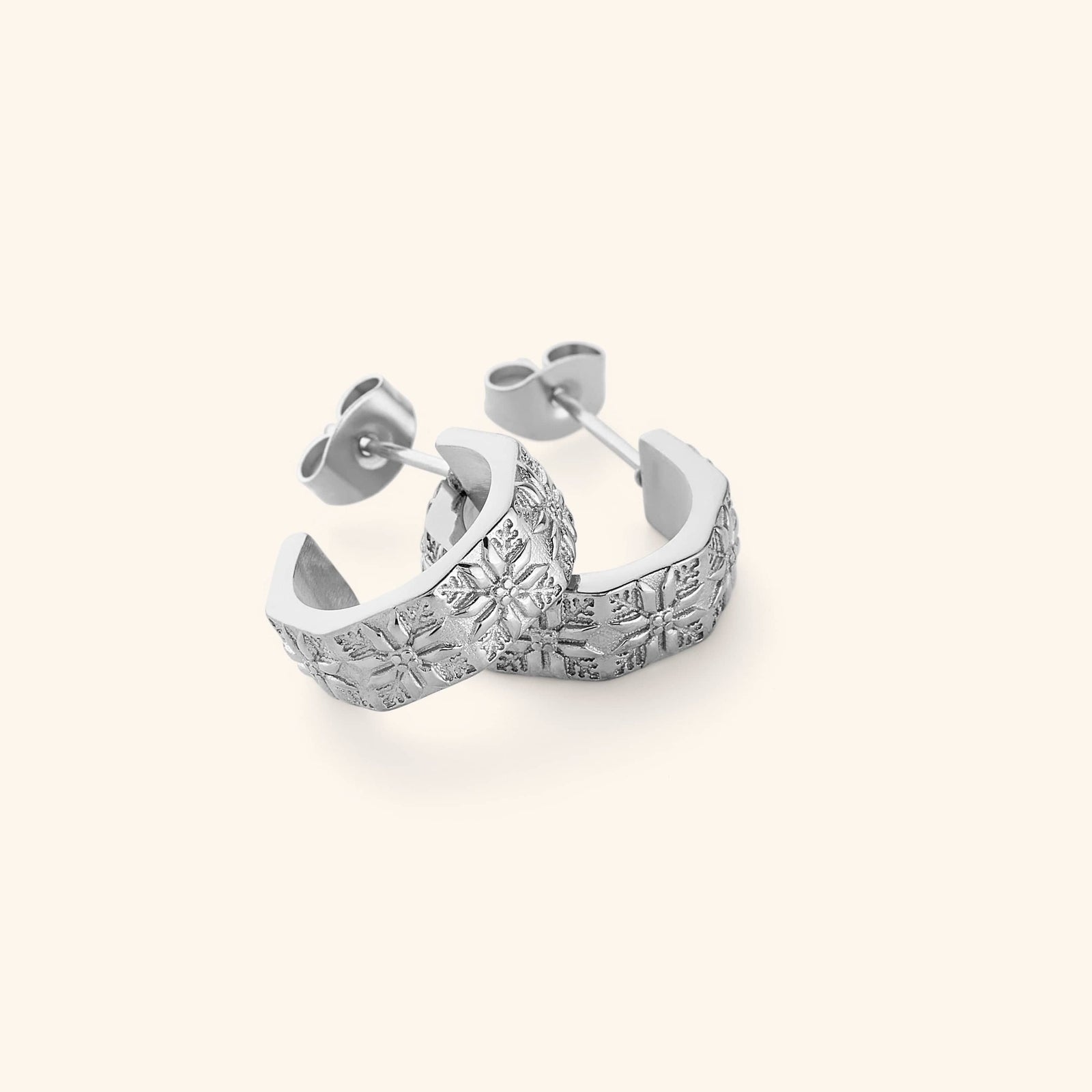 A pair of silver thick hoop earrings traced with tatreez.