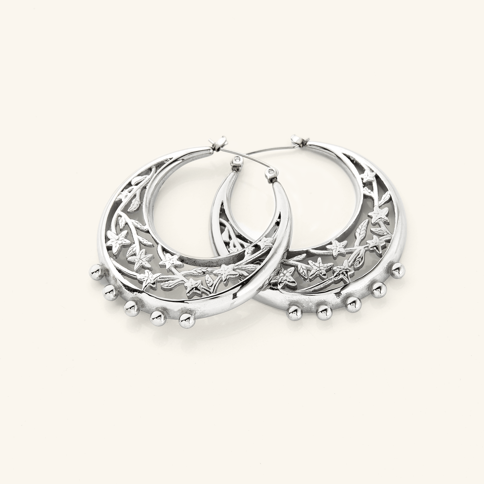 The Jasmine Crescent Hoop Earrings in a polished silver finish, showcasing a chunky hoop design adorned with an intricate jasmine vine that gracefully weaves through the crescent shape, blending celestial inspiration with botanical beauty