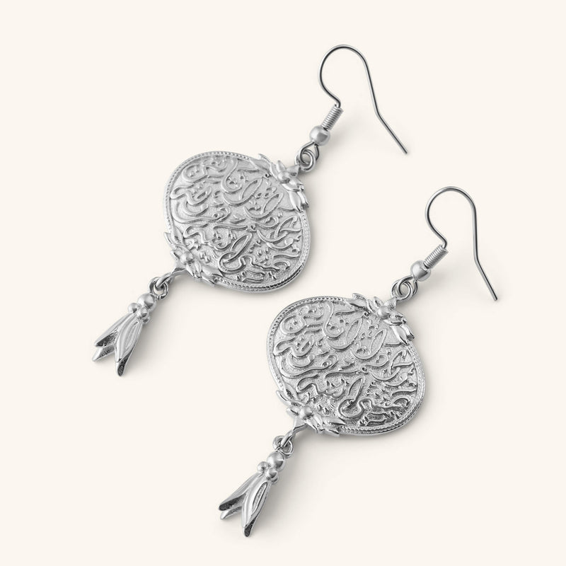 “Walk to Me pimage_ and I'll run to you” Medallion Earrings in silver pimage_ featuring engraved Arabic calligraphy and a small dangling charm.