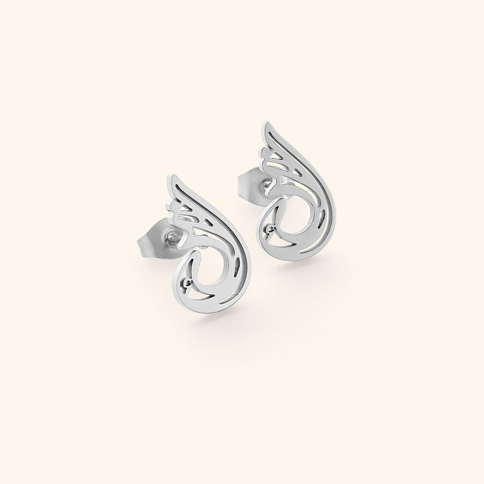 A pair of silver "Serenity Earrings" from the Aadil x Nominal collection. The earrings feature a unique, abstract, teardrop-like design with swirling cut-out details. The image is a product shot, likely showcasing the design and craftsmanship of the earrings.