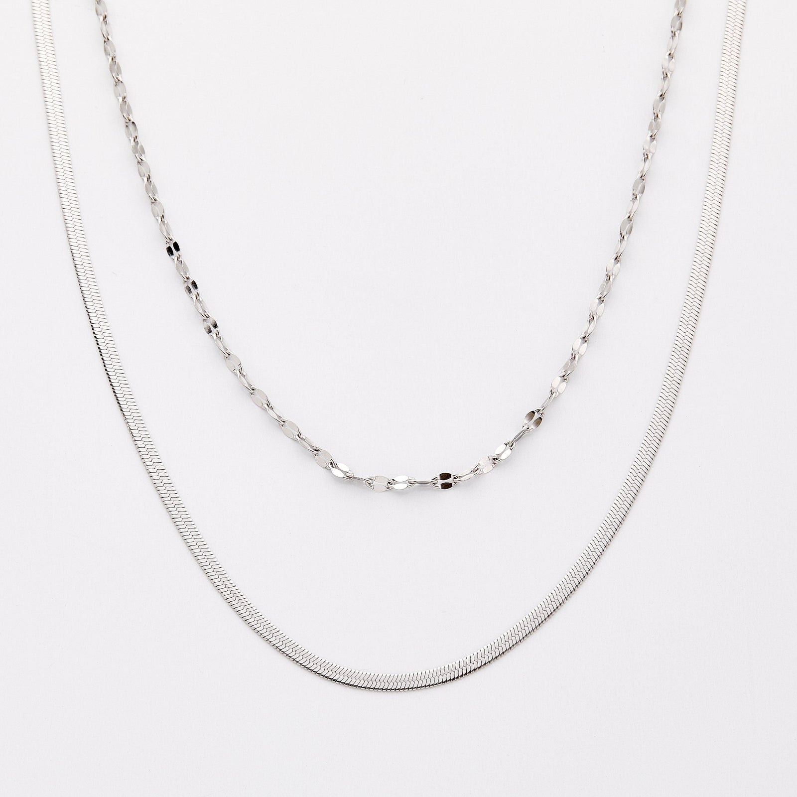 Silver necklace set with a herringbone chain and a flutter chain, displayed on a light background.