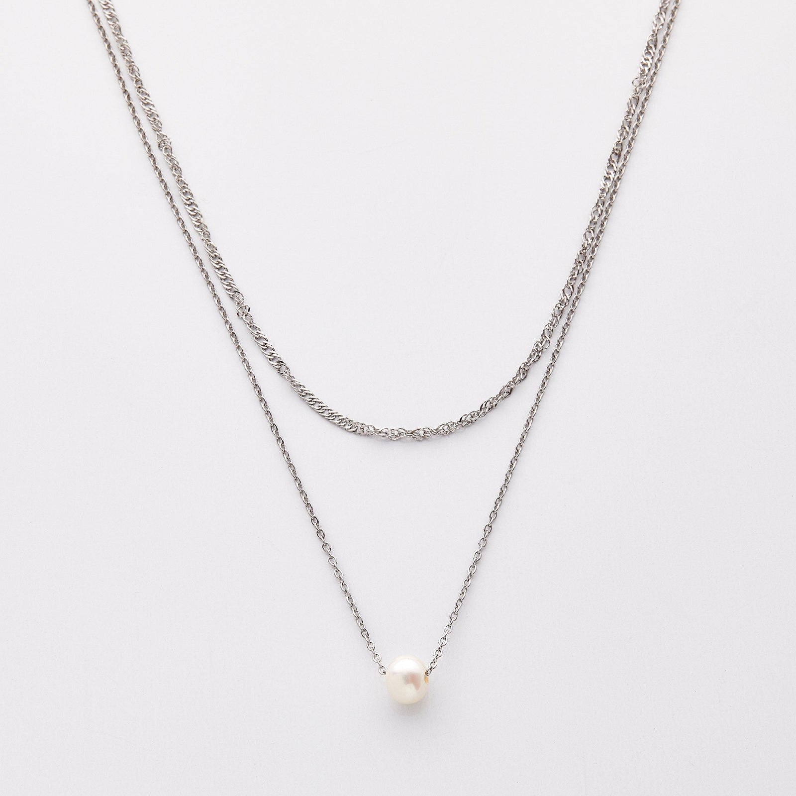 Layered silver necklaces featuring a twisted chain and a delicate chain with a single white pearl pendant, displayed on a light background.