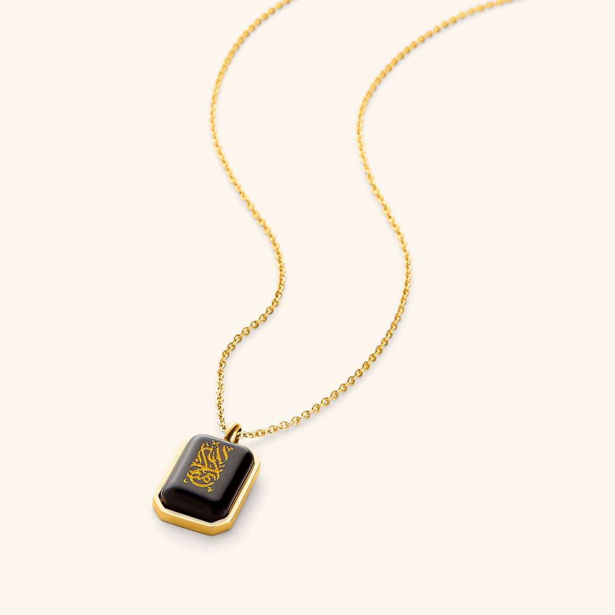 Gold chain necklace with a rectangular black obsidian pendant engraved in Arabic calligraphy reading "Alhamdulillah," framed with a gold border, displayed on a light background.