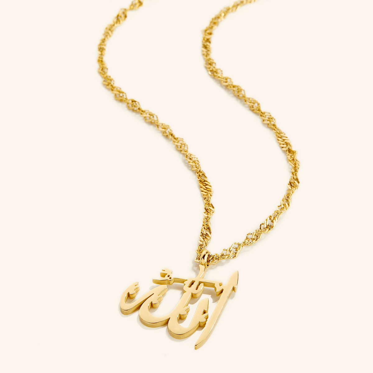 Photo of an 18k gold plated necklace with a pendant that features the Arabic Calligraphy for Allah.