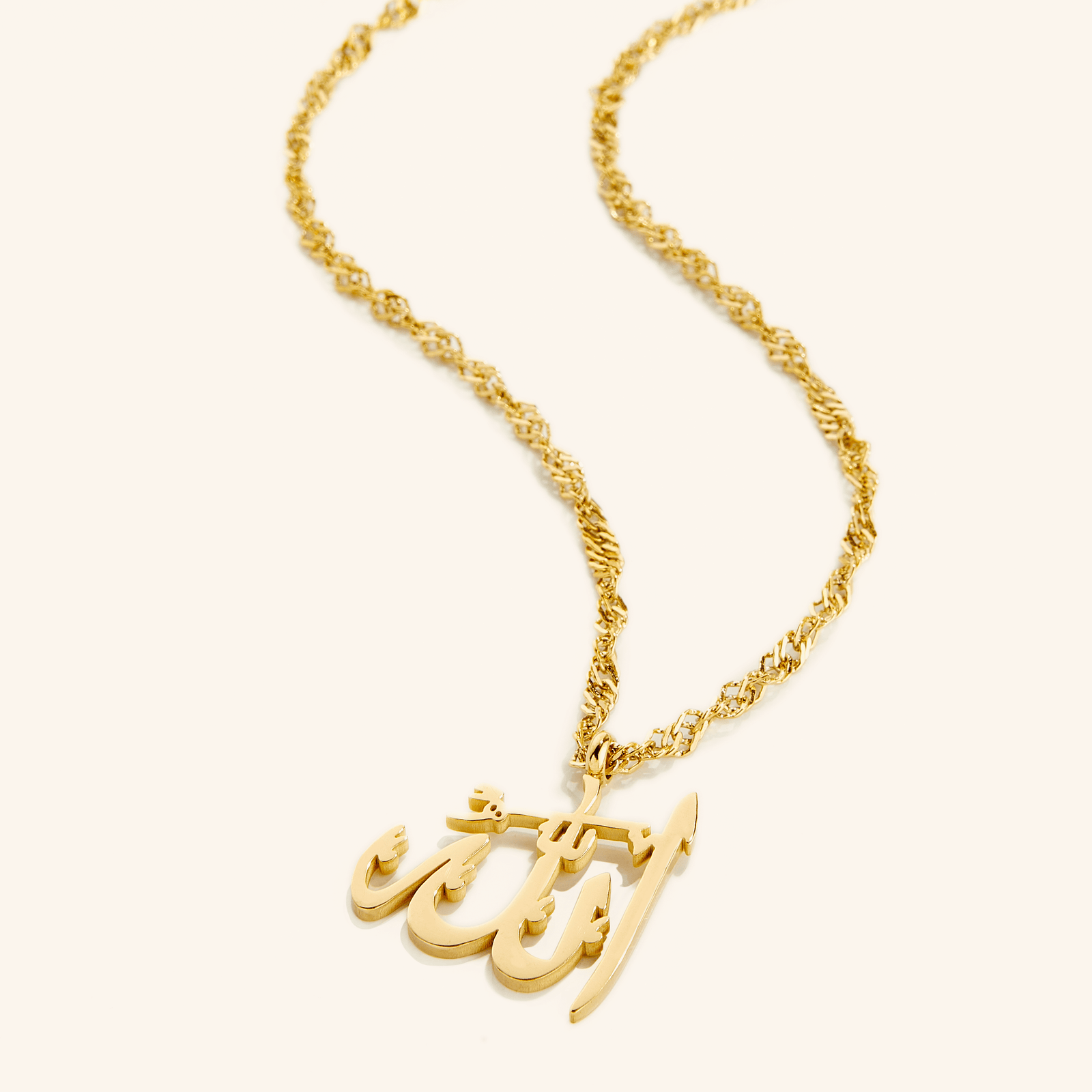 Photo of an 18k gold plated necklace with a pendant that features the Arabic Calligraphy for Allah.